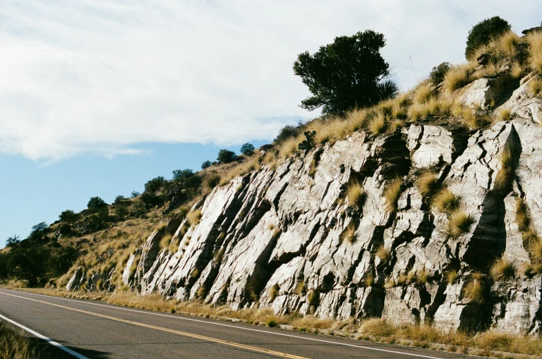 an empty highway with rock formations along it