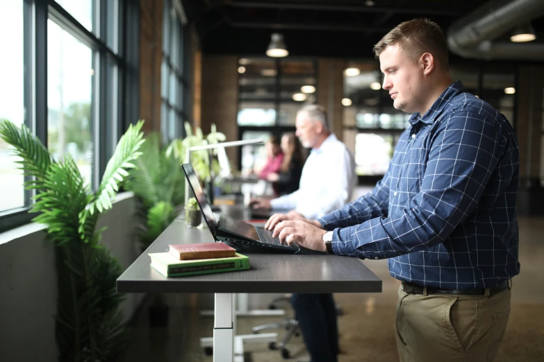 a man at a desk on a laptop looking out a window