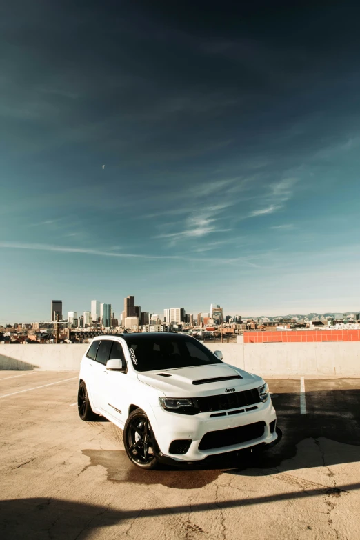 a white dodge charge parked in front of a tall building