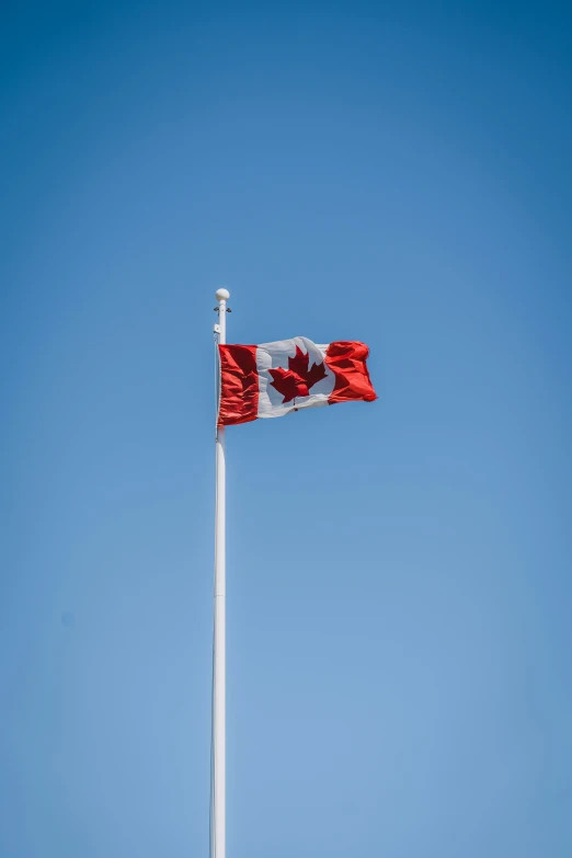 a canadian flag flying in the sky above a building