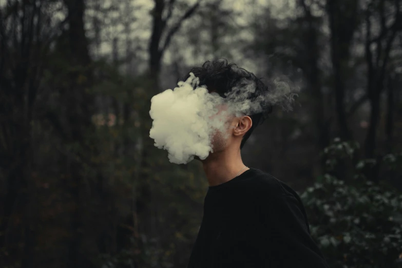 a man in black shirt blowing white smoke into his mouth