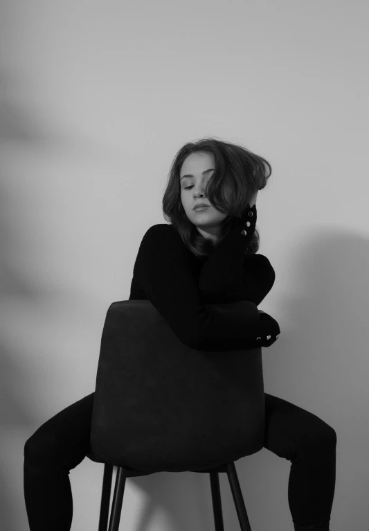 black and white image of a woman sitting on a chair