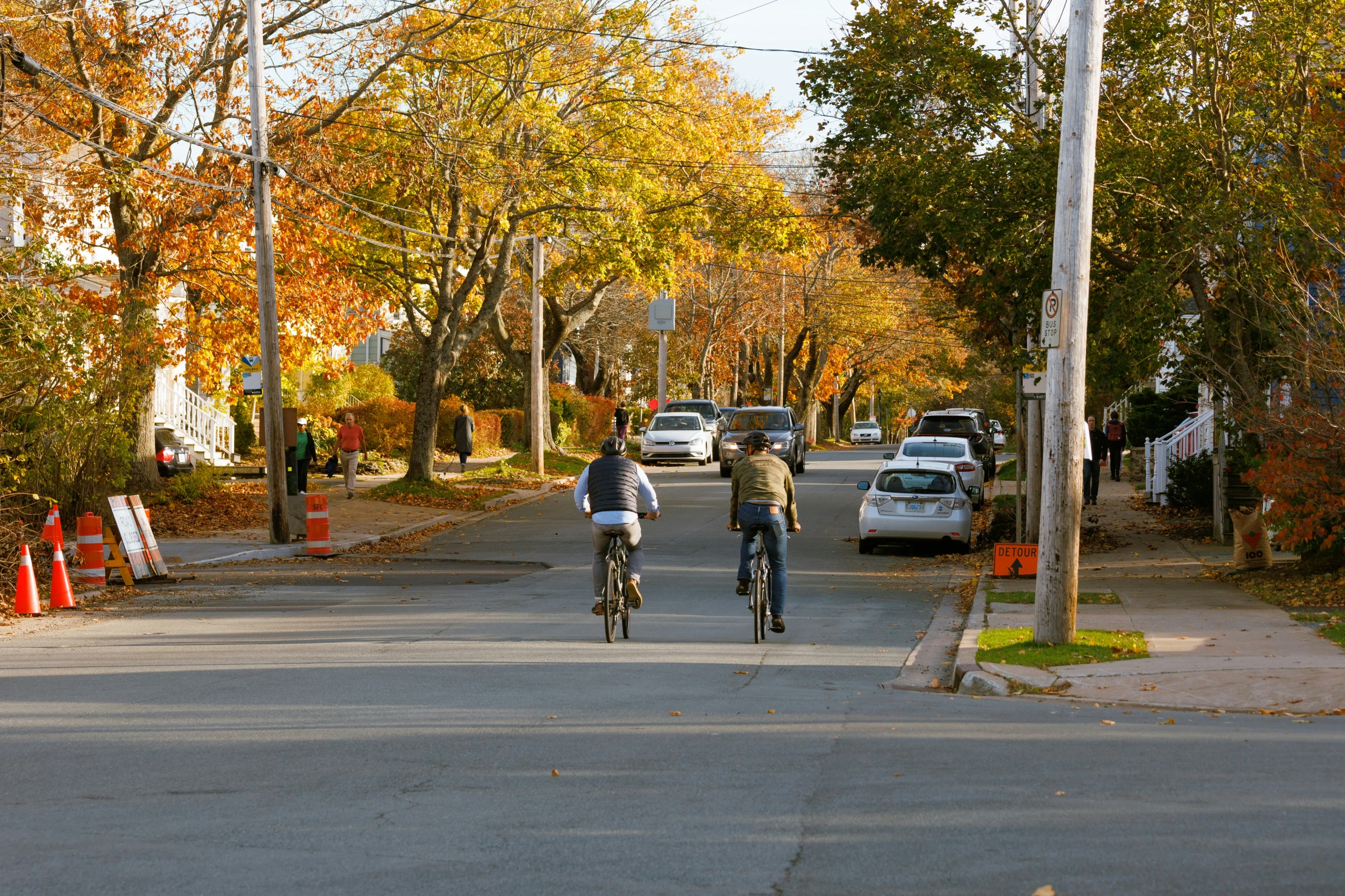 two people riding bikes down a street next to traffic cones