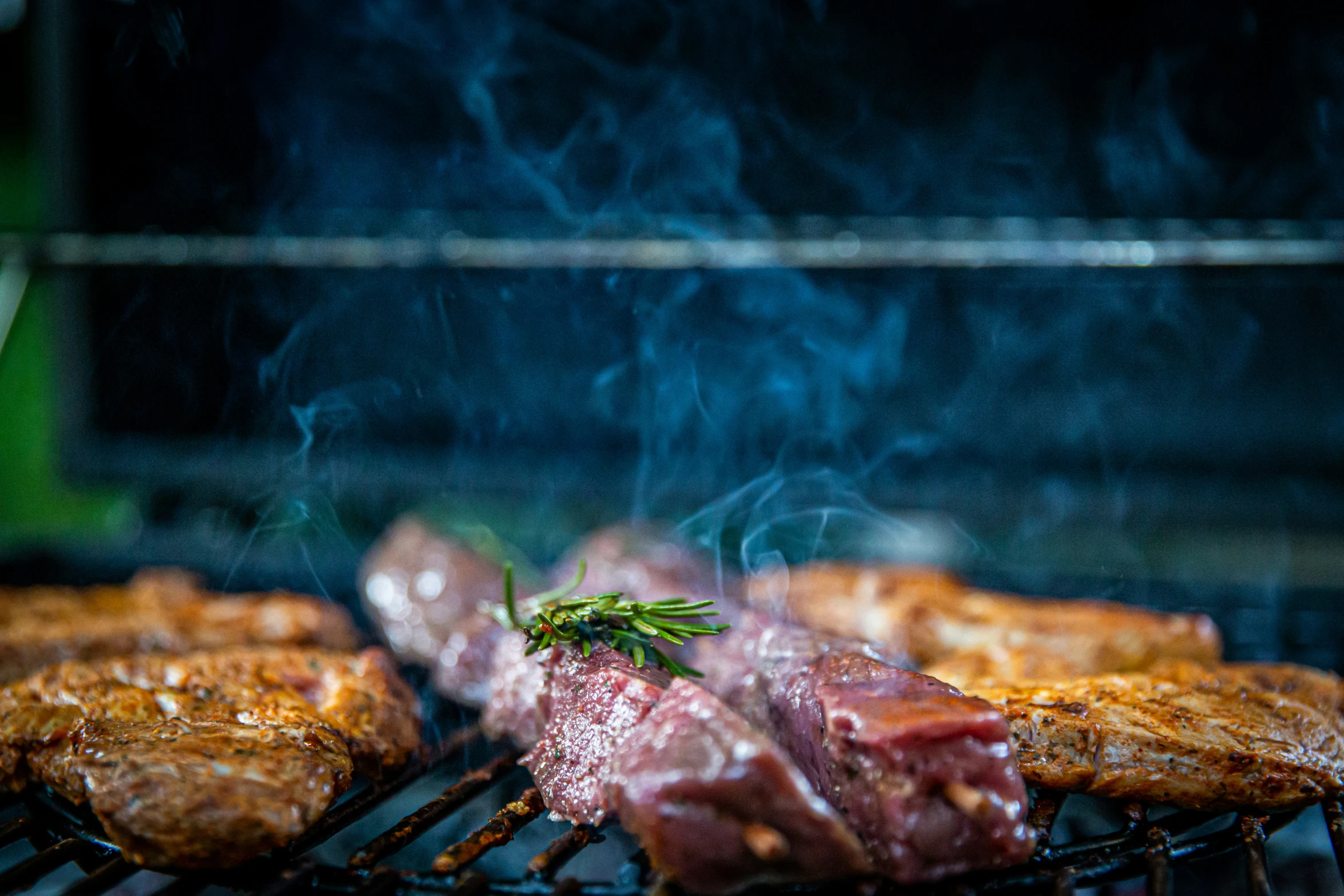 steaks and other meat on the grill being cooked