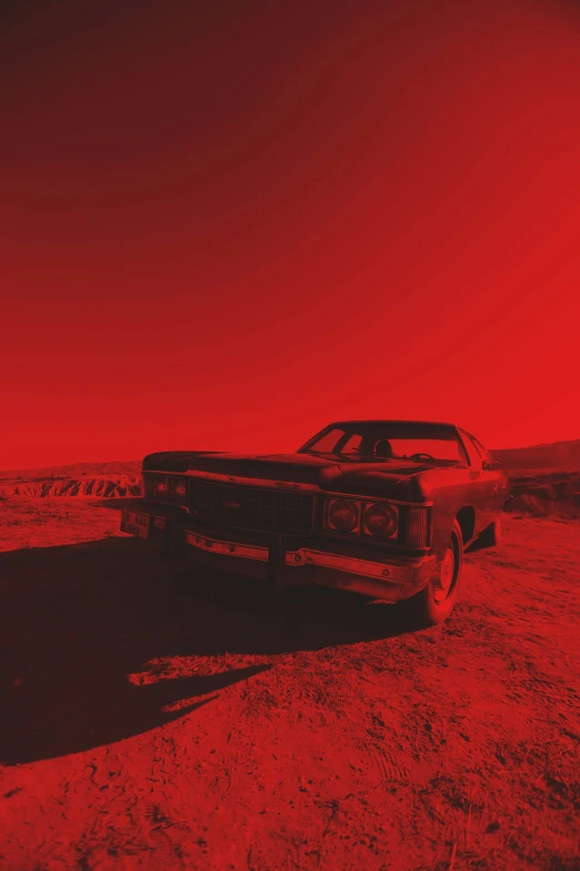an old car sitting on top of a red dirt field