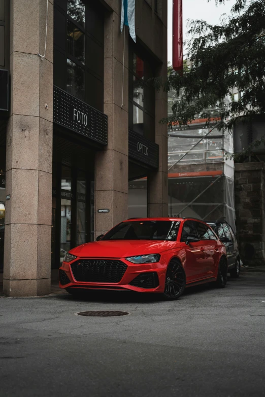 a red car is parked outside a tall building