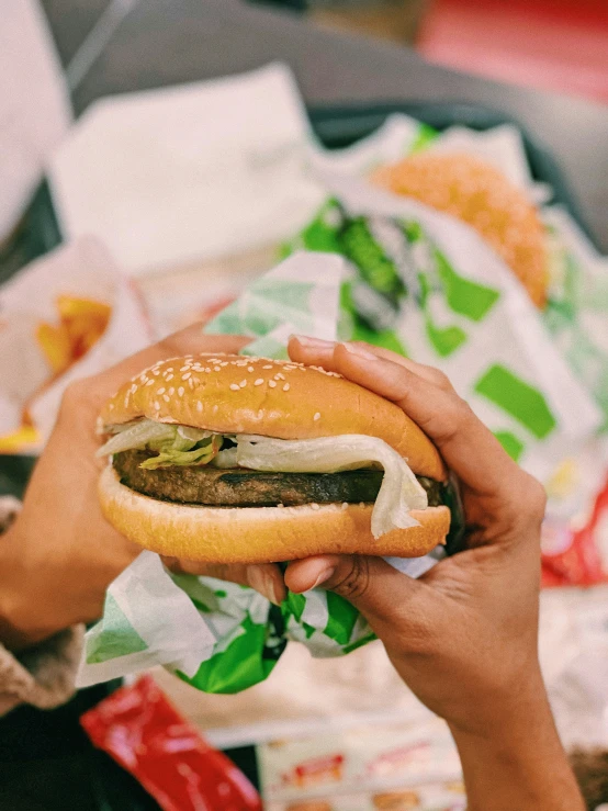 hand holding a hamburger and bun in front of them