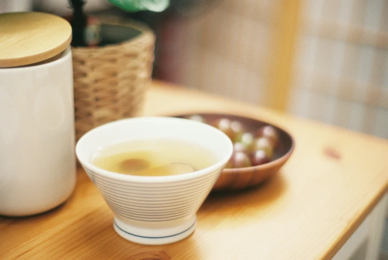 a cup of tea and a canister are on a wooden table