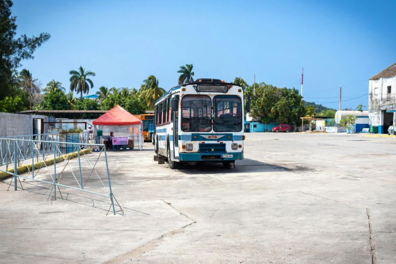 the bus has stopped on the road by the fence