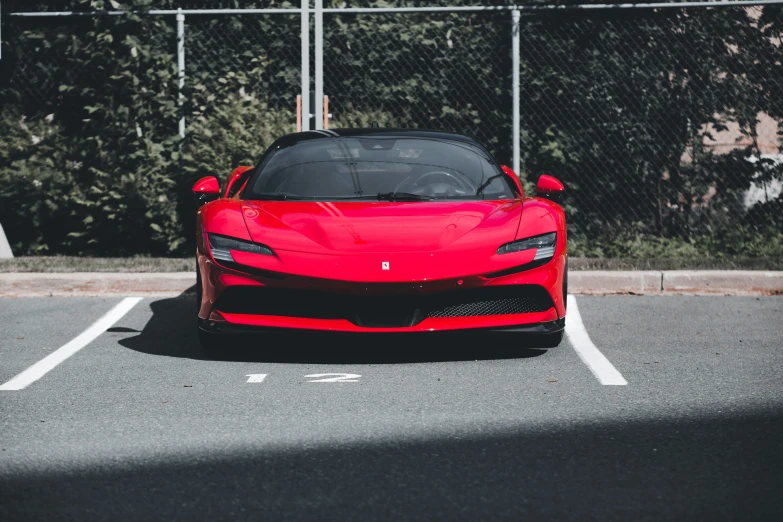 red sports car in parking lot with fence in background