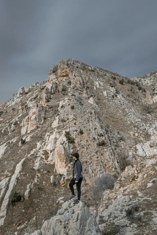 a person standing on top of a rocky mountain with his legs crossed