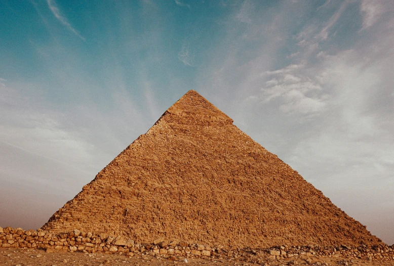 a large building next to some dirt rocks and a sky background