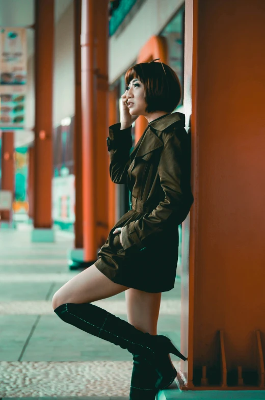 a young woman leaning against an orange pillar