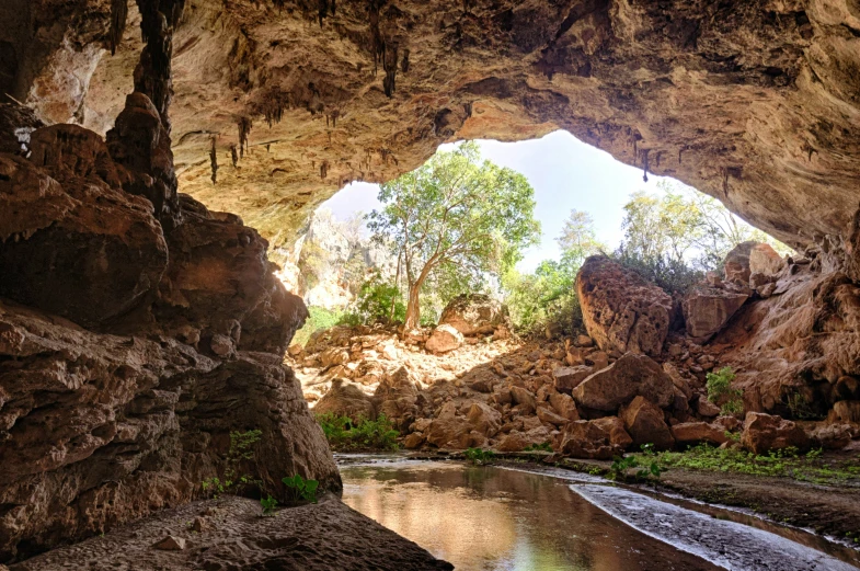 a large cave entrance in the middle of a rocky valley