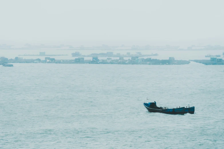 a lone blue boat floating in the middle of the ocean