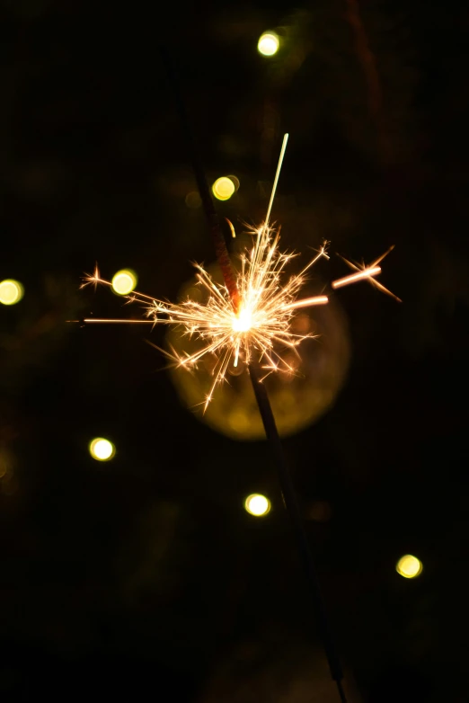 a sparkler is glowing on the dark night sky