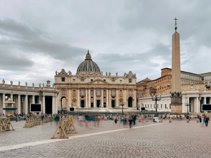 a large building and a big pillar with people walking around