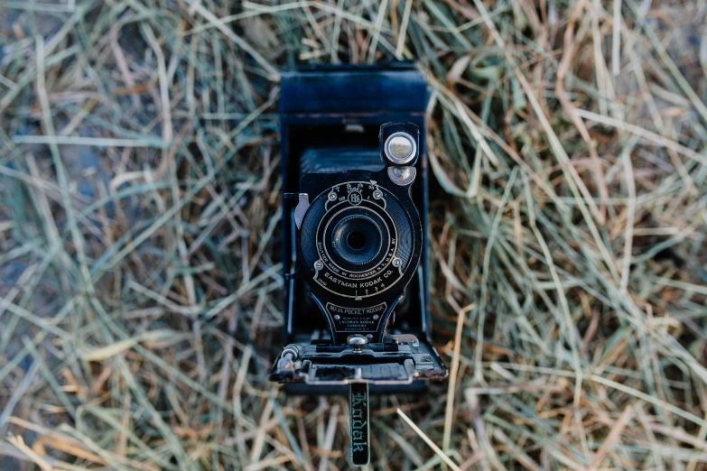 a broken camera standing in grass looking down at it