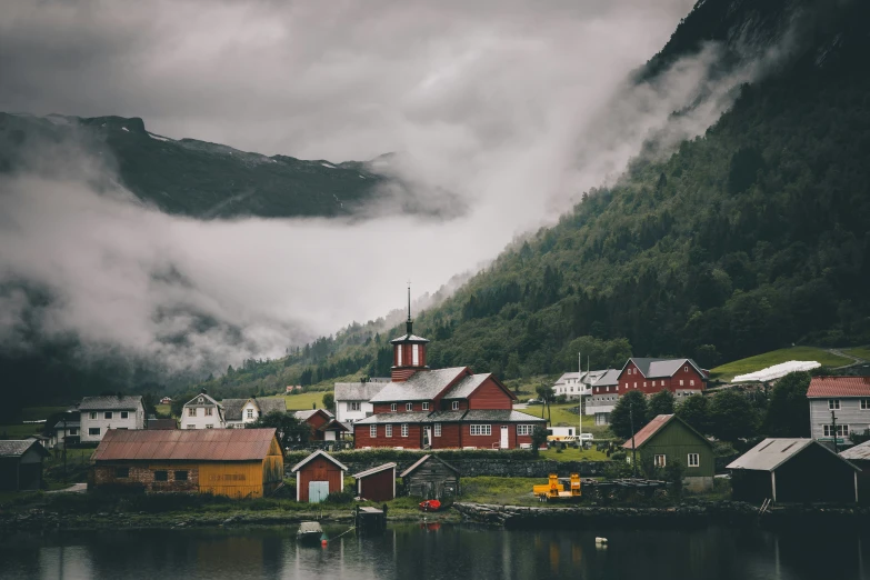 the small village with a steep cliff in the background is surrounded by mist