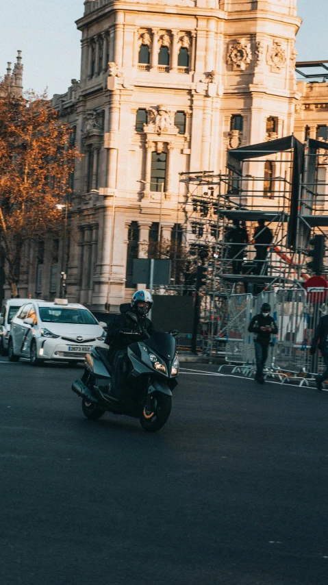 a motorcycle rider in a street near some buildings