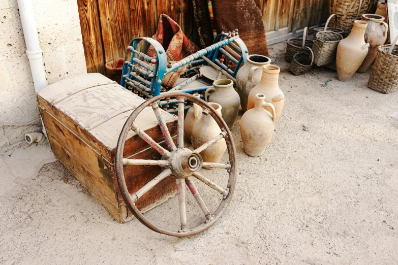 vases sitting next to a cart with an old wooden wheel