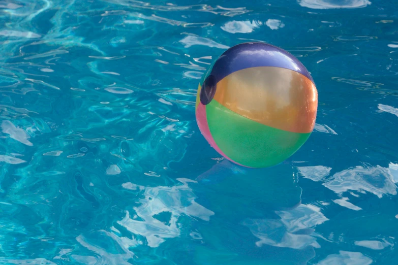 an inflatable ball floating in water at the edge of a pool