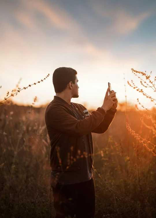 a man stands in a field, holding an object in his hand