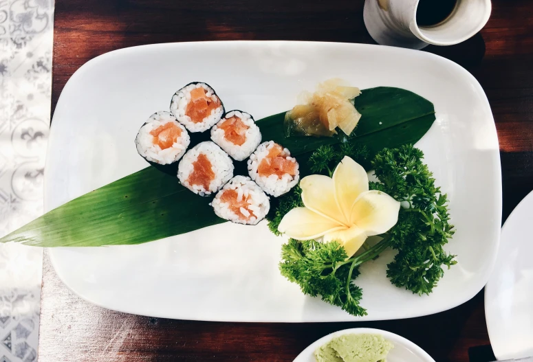 sushi rolls with flower and vegetables sit on a white plate