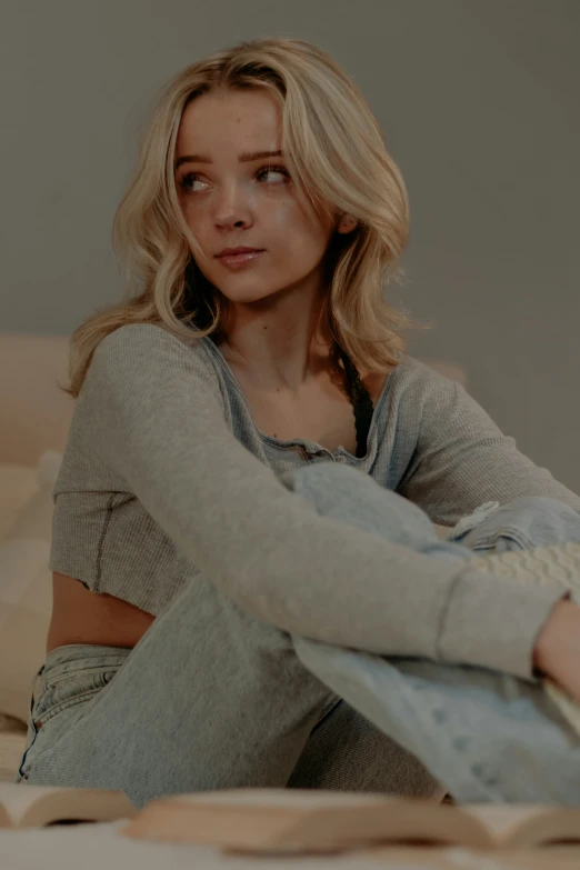 a pretty blonde haired woman sitting on a bed