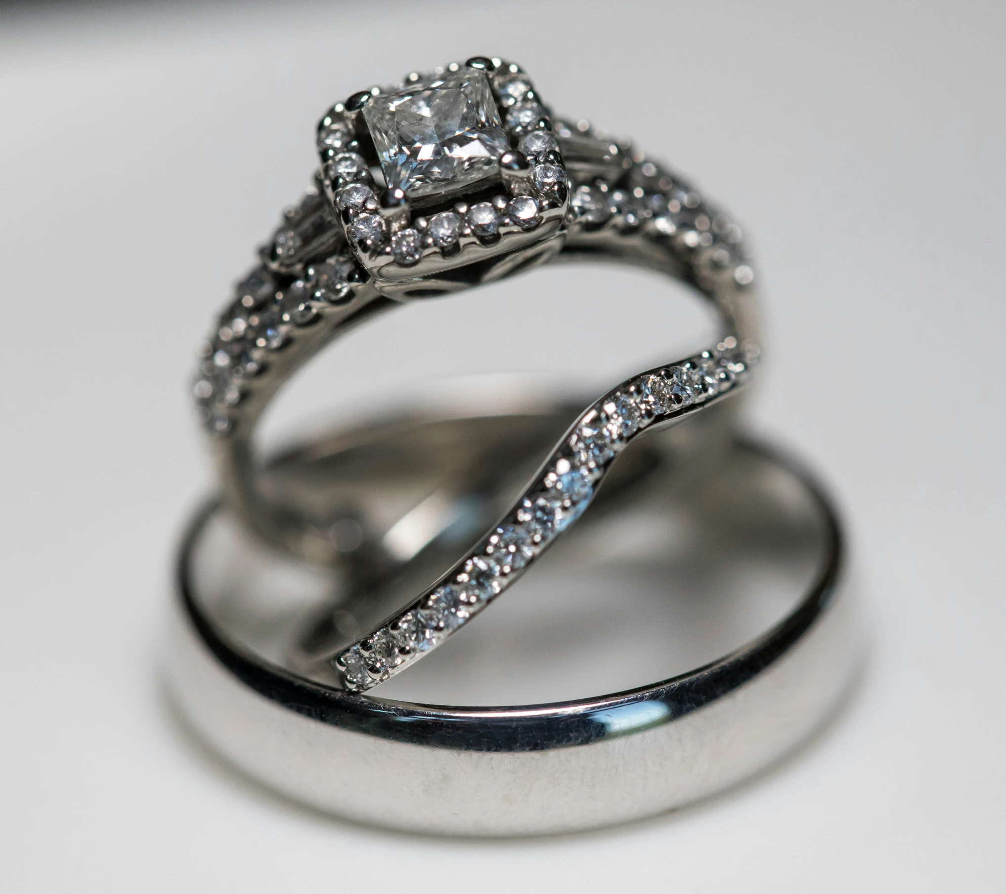 two engagement and wedding rings on a white surface