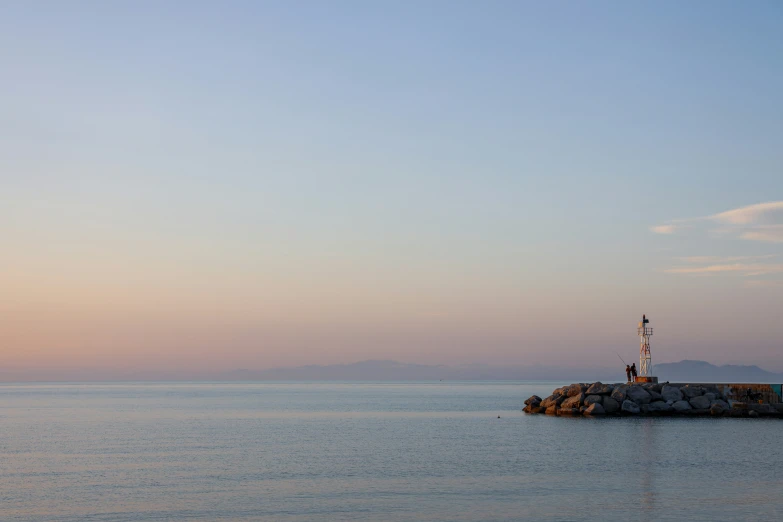 a boat sitting in the water by a lighthouse