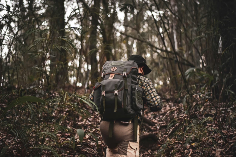 a man hiking through the woods wearing a back pack