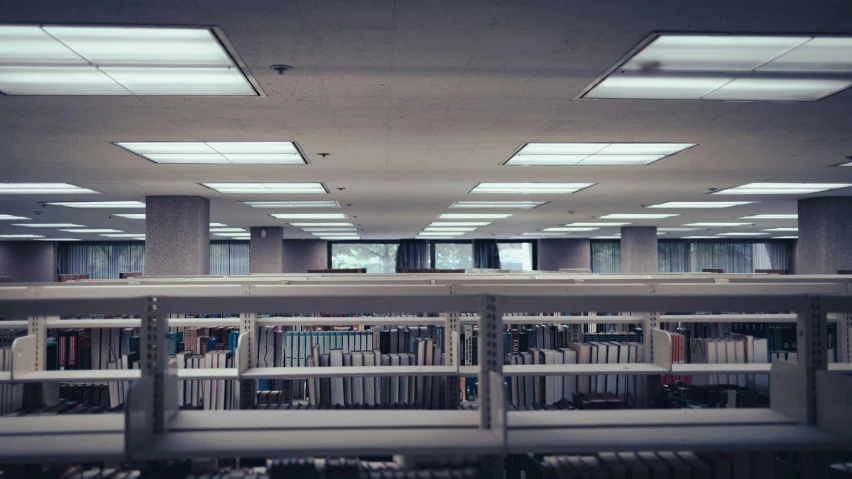 long table with several books in the middle of a large room filled with rows of chairs