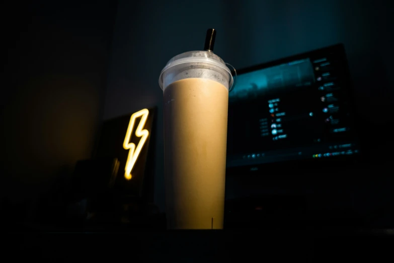 a glass with a straw is next to a computer