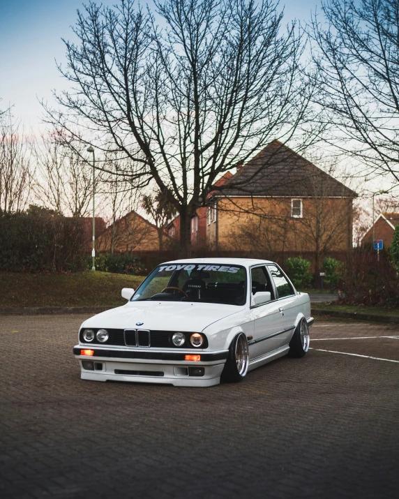 an old white bmw parked in a parking lot