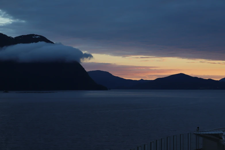 a mountain is shown with the clouds and some water below