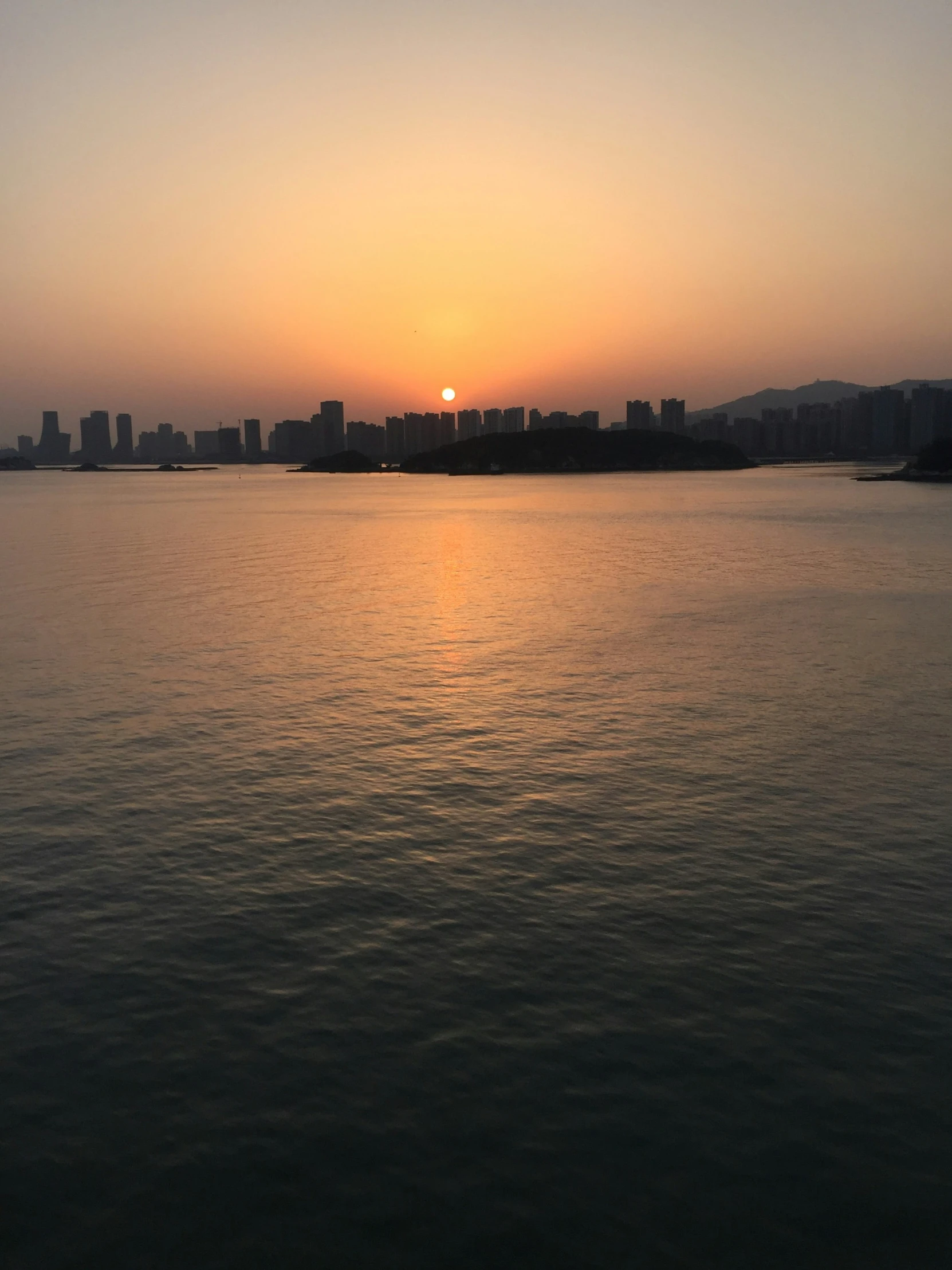 a beautiful sunset on the sea with a city in the background