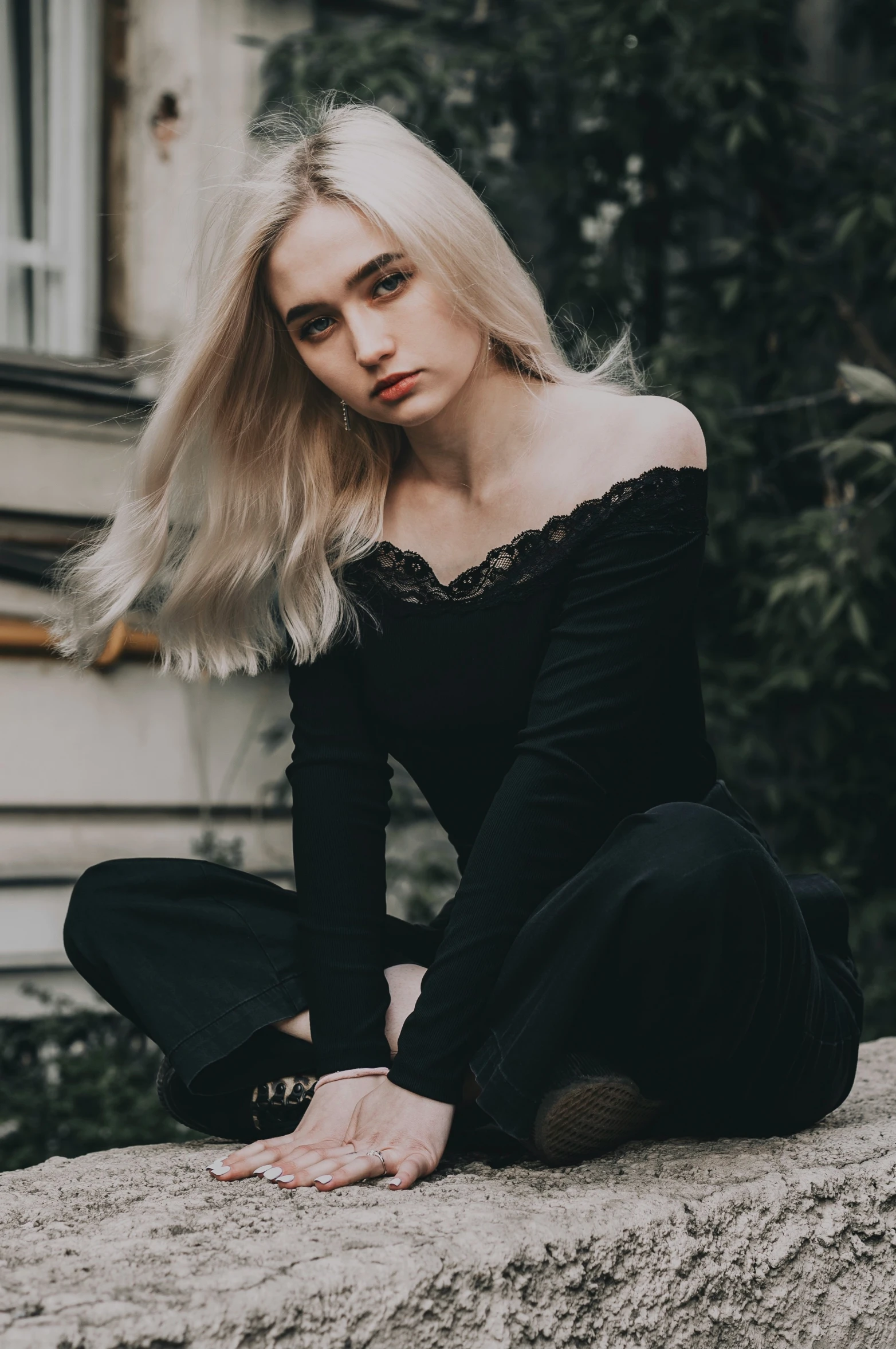 woman with blonde hair sitting on the edge of concrete wall