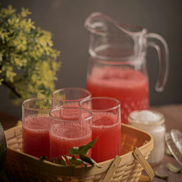 glasses filled with watermelon juice sitting on top of a basket
