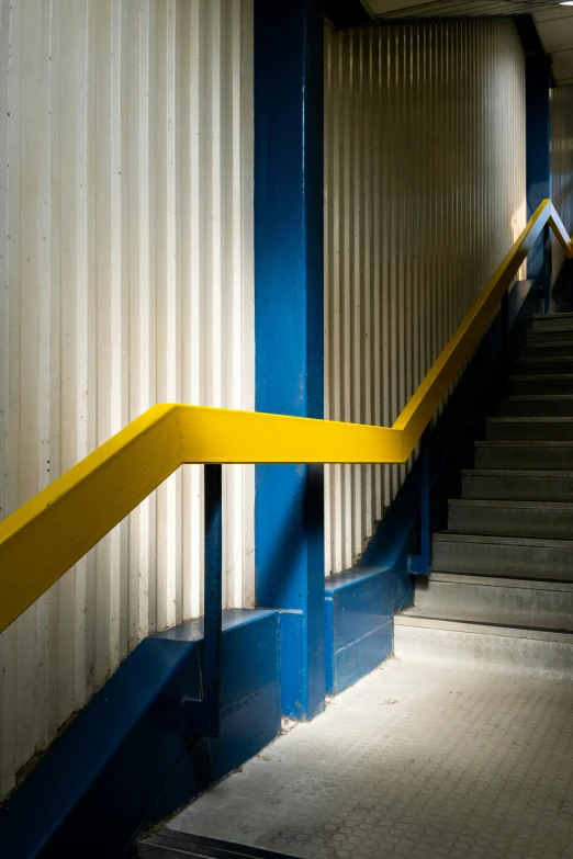 some stairs with a yellow railing by some blue and white building