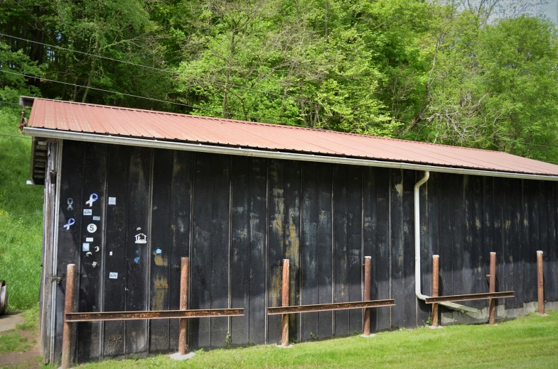 a barn sitting next to the trees with a tin roof