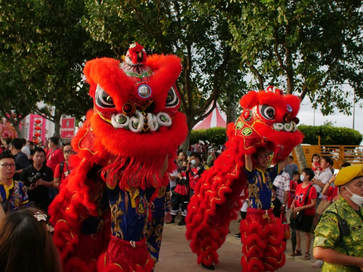 two red dragon dance costumes with people watching