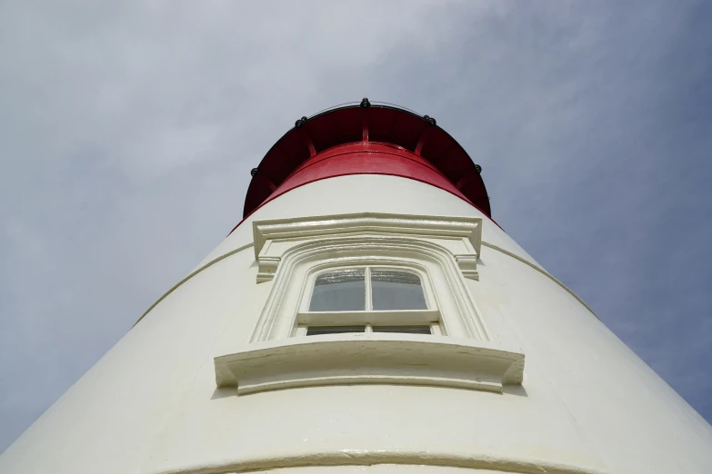 a red light house that is tall and white