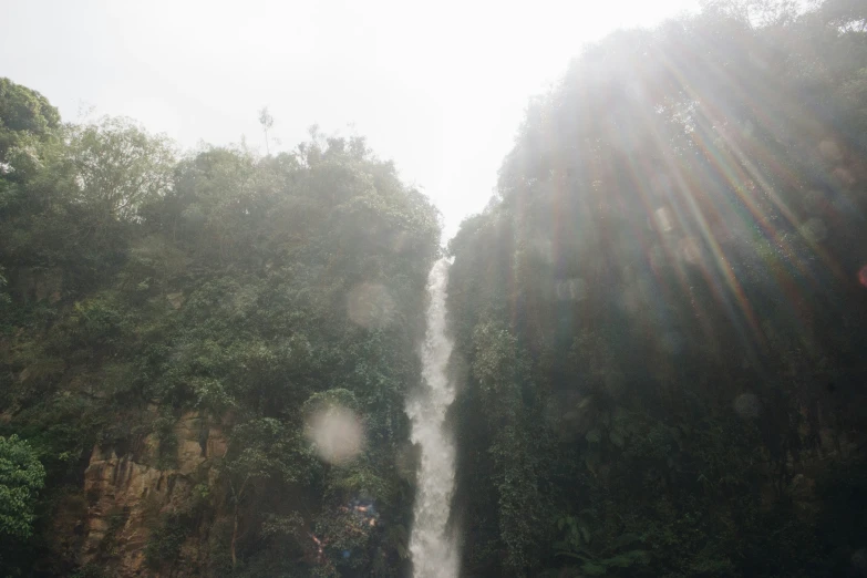 some people are standing in the water near a tall waterfall