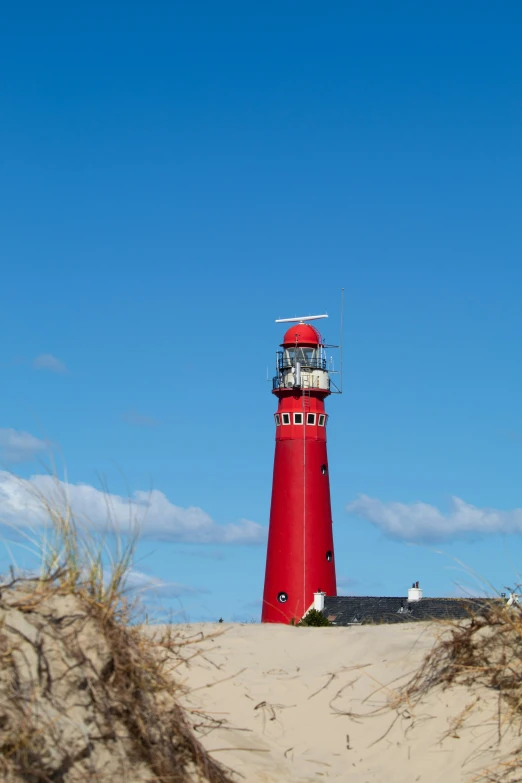a red lighthouse with sand dunes on it