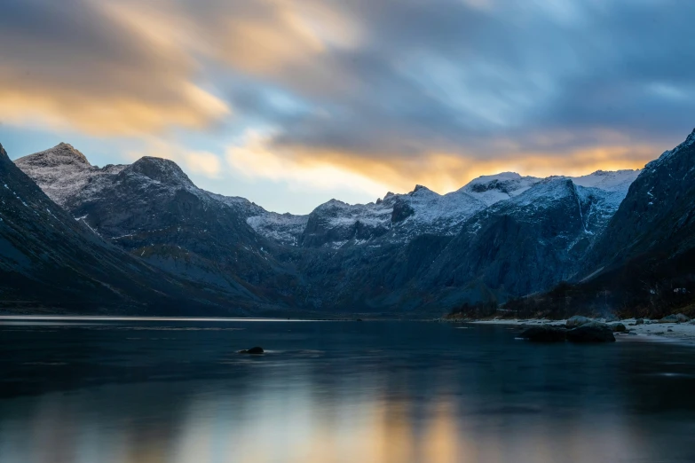 the snow capped mountains and trees are reflecting in the lake