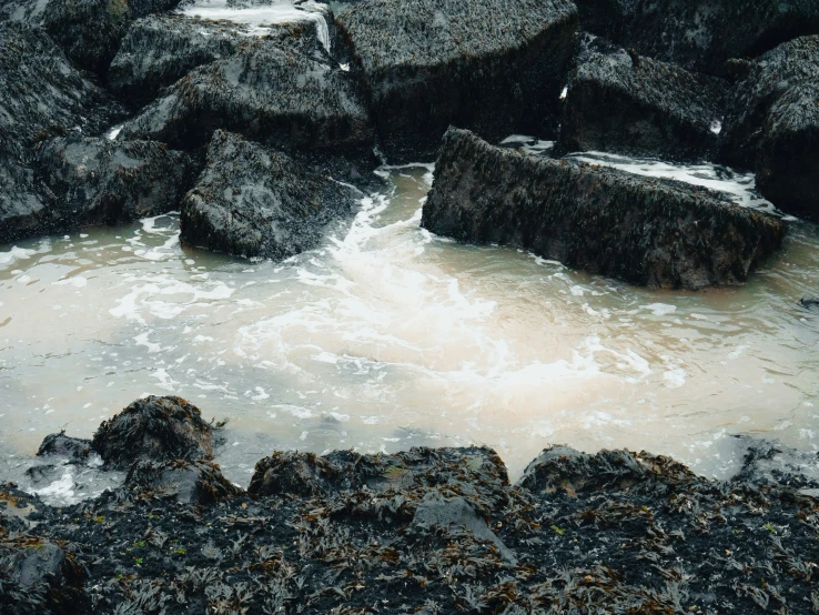 there is the tide coming out from behind the rocks