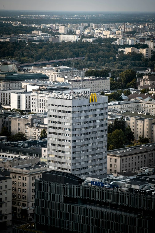 a tall building with the letter m on it stands above some other buildings in an urban area