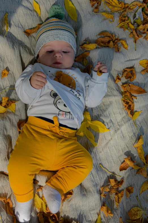 a little baby is laying on a bed with autumn leaves