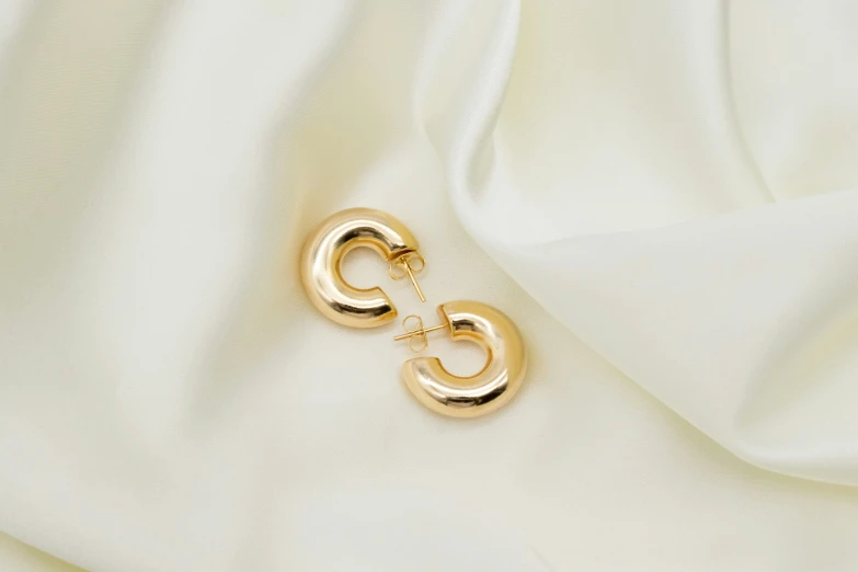 a white satin with two golden rings hanging from it